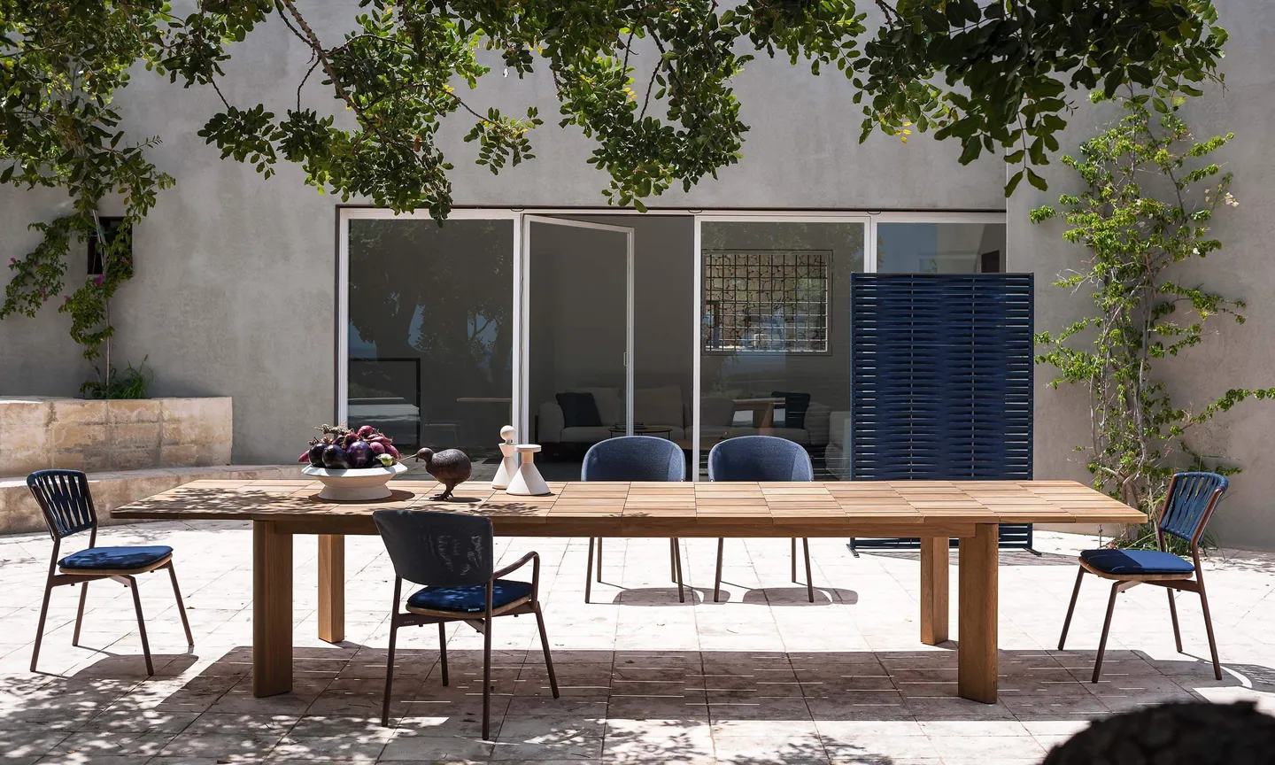 RODA Brick teak table set for dinner under a veranda, RODA garden furniture catalog photograph