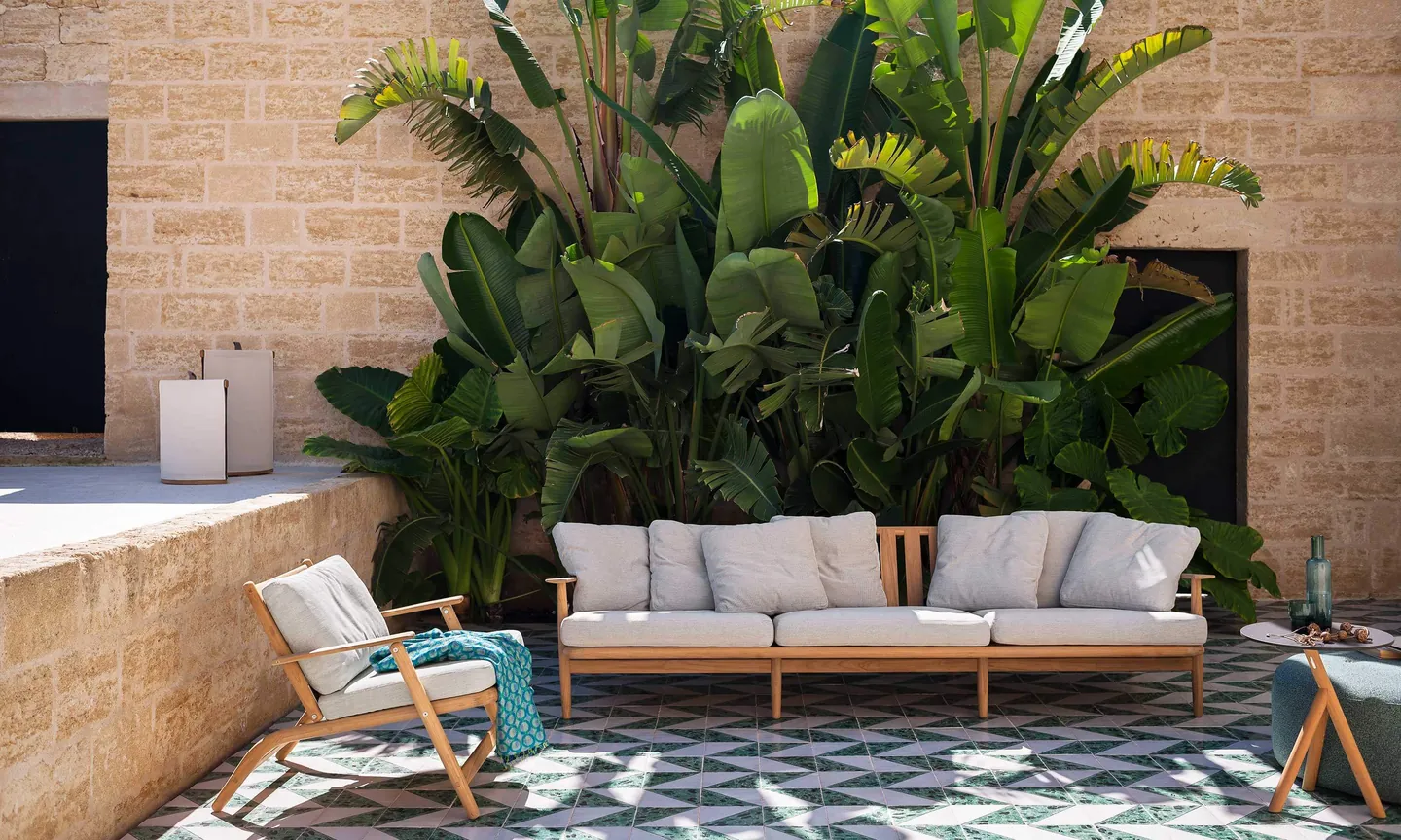 RODA Levante teak dining table and armchairs on a terrace, Italian outdoor furniture catalog photograph