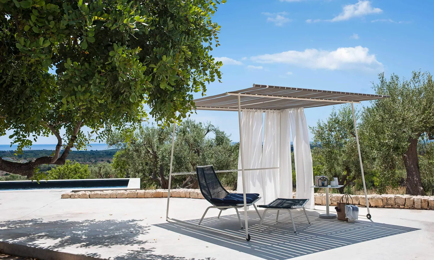 RODA Ombrina gazebo with curtains over lounge chairs in a garden, Italian outdoor furniture catalog photograph