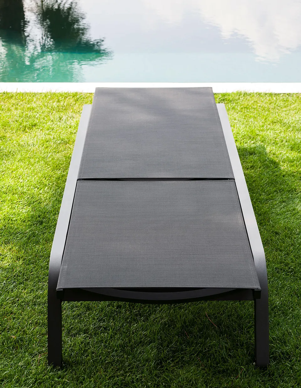RODA Surfer sun loungers lined up beside a swimming pool, RODA patio furniture catalog photograph