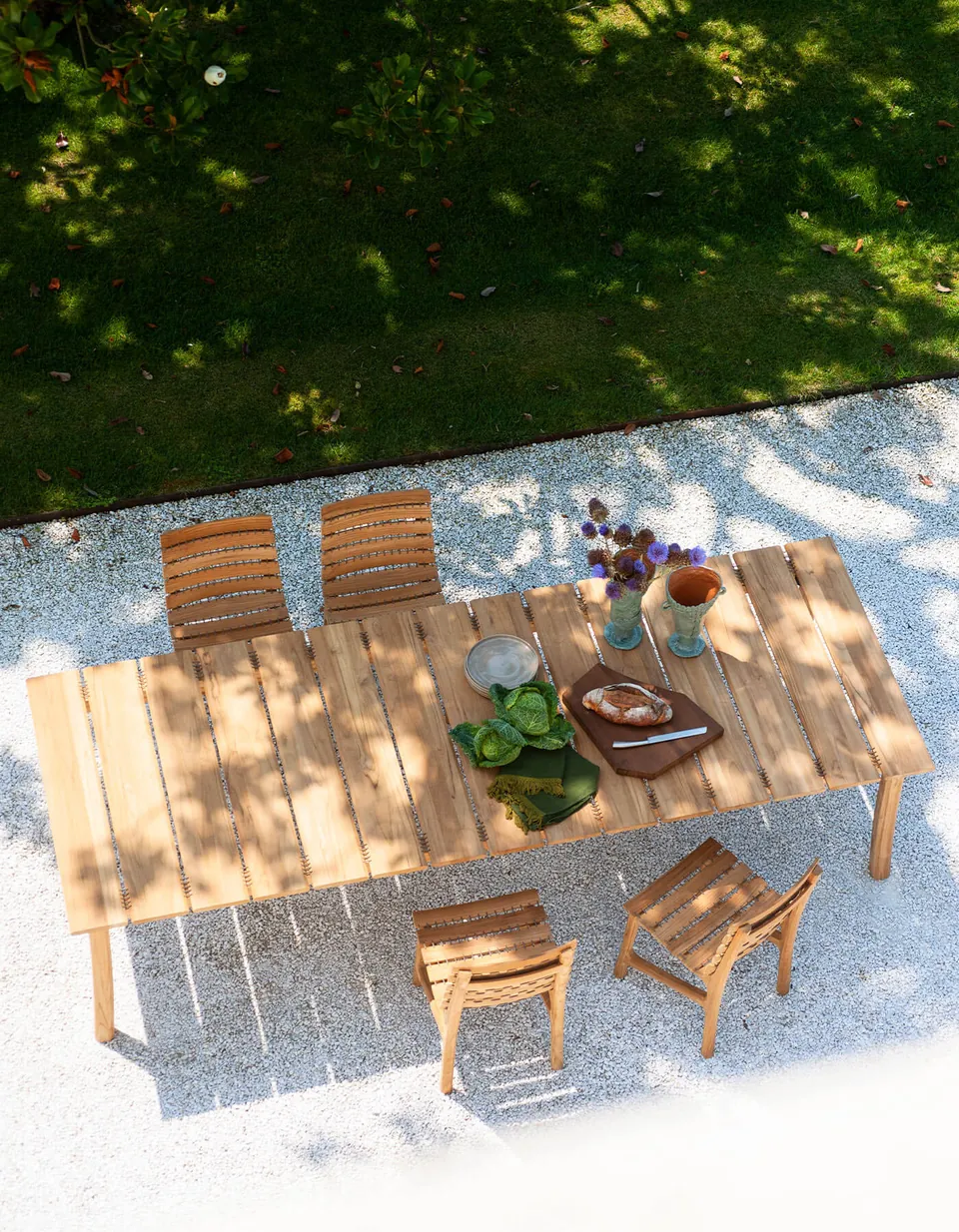 RODA Teseo teak dining table and chairs in a garden, RODA furniture catalog photograph
